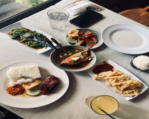 A variety of traditional Indonesian dishes like tempeh, tofu, and clear vegetable soup laid out on a dining table