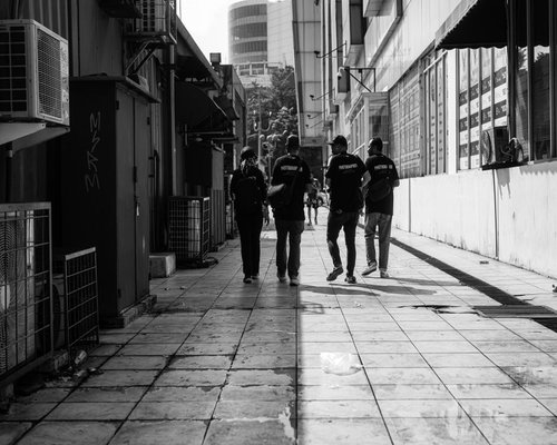 A group of people walking casually on a pedestrian path near a modern office building in Jakarta