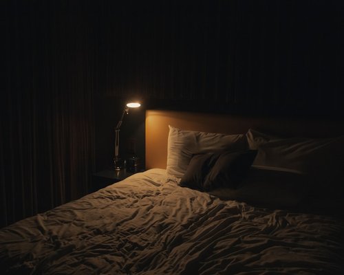 A tidy bedroom setup with dim, warm lighting creating a relaxing nighttime atmosphere